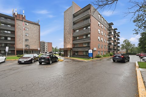 A parking lot with cars and two buildings in the background.