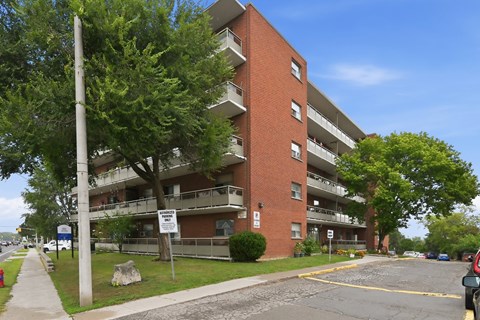 A red brick apartment building with a parking lot in front.