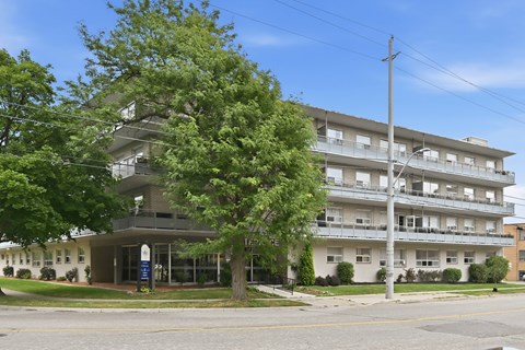 A large apartment building with a tree in front of it.