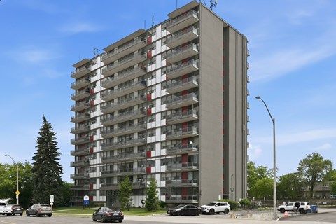 A tall residential building with cars parked in front.