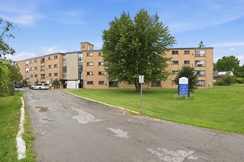 A street view of a residential area with apartment buildings and a blue recycling bin.
