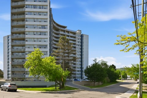 A tall building with a curved design and balconies on the upper floors.