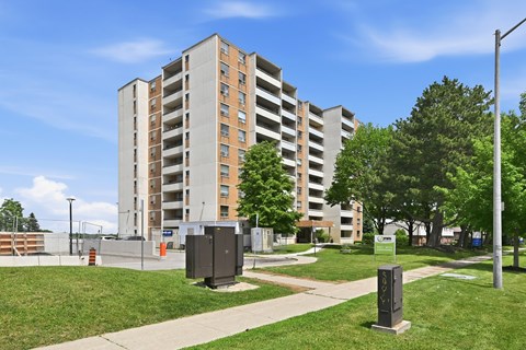 A tall apartment building with a grassy area in front of it.