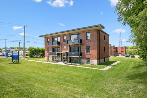 A red brick building with a green lawn in front.