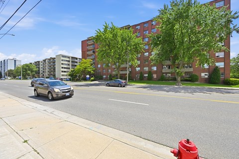 A red fire hydrant is on the sidewalk next to a street.