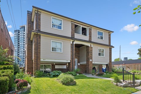 A two-story house with a well-maintained lawn and a small garden in front.
