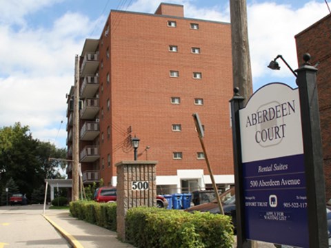 A sign for Aberdeen Court is in front of a brick building.