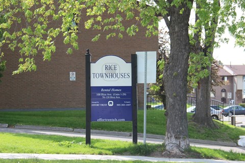 A sign for Rice Townhouses stands in front of a brick building.