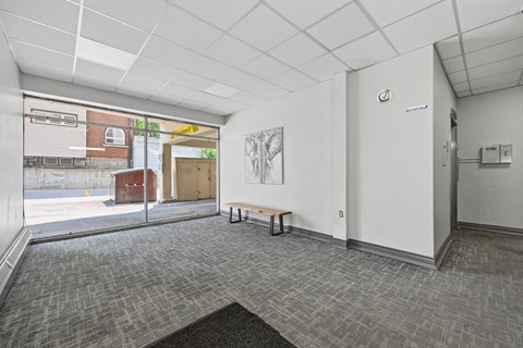 A room with a grey carpet and a white wall with a door.