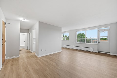 A spacious room with wooden floors and white walls.