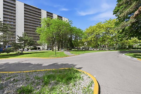 A road with a yellow line on the side and a building in the background.