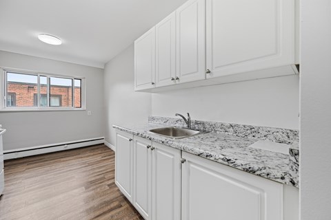 A kitchen with white cabinets and a marble countertop.