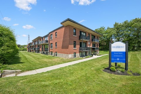 A blue sign stands in front of a brick building.