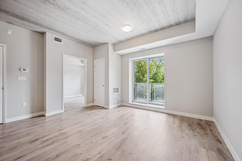A spacious room with wooden floors and a large window.