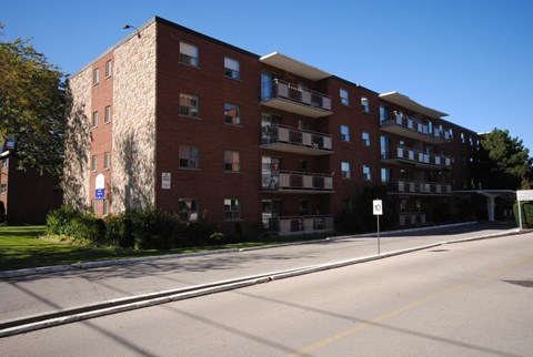A large red brick apartment building with a white sign on the right side.