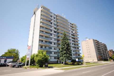 A tall residential building with a parking lot in front.