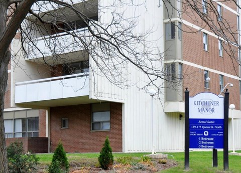 A sign for Kitchener Manor is in front of a brick building.