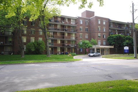 A large brick apartment building with a tree in front of it.