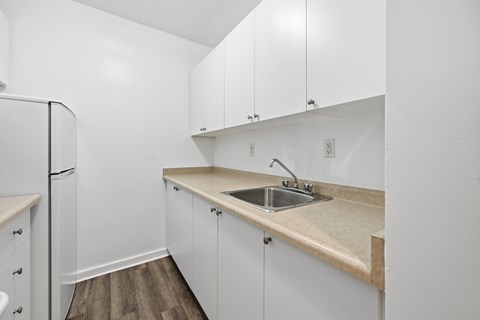 A kitchen with white cabinets and a beige countertop.