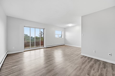 A spacious room with wooden flooring and a large window.