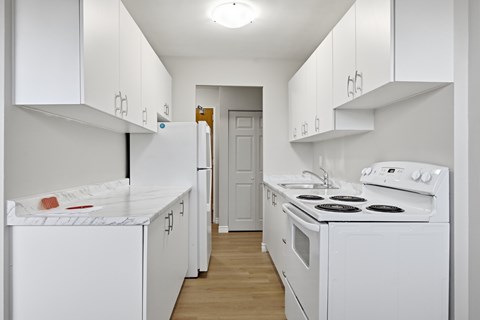 A white kitchen with a stove, oven, and refrigerator.