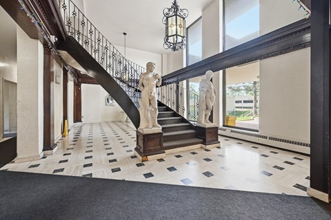 A marble statue stands on a staircase with a black railing.