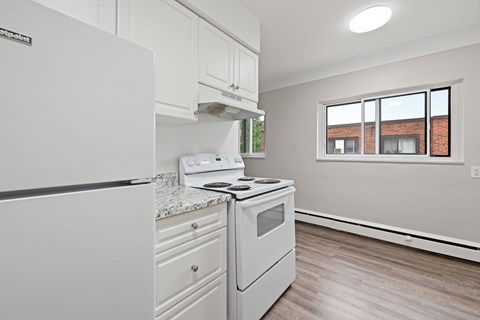 A white kitchen with a fridge, stove and oven.
