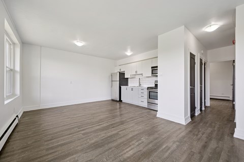 A spacious kitchen with white cabinets and a wooden floor.