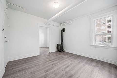 A room with a wood floor and a window showing a building outside.