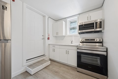 A kitchen with white cabinets and a stainless steel refrigerator.
