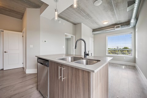 A modern kitchen with a stainless steel sink and wooden cabinets.