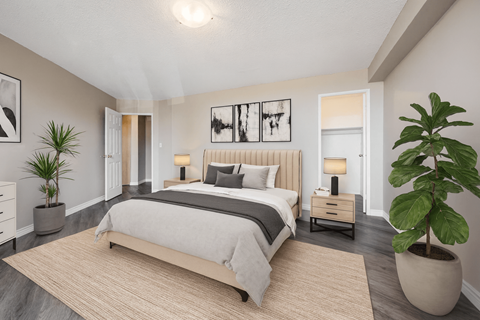 A bedroom with a large bed and a plant on the side table.