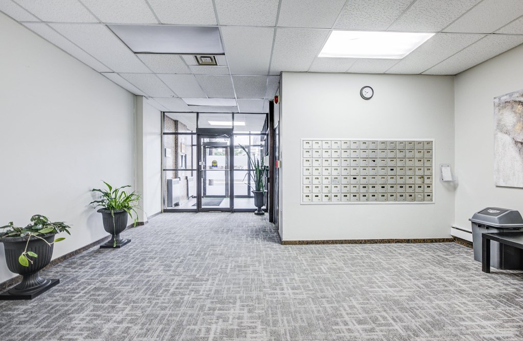 A hallway with a carpeted floor, a white wall, and a calendar on the wall.