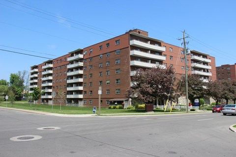 A large red brick apartment building with a parking lot in front.