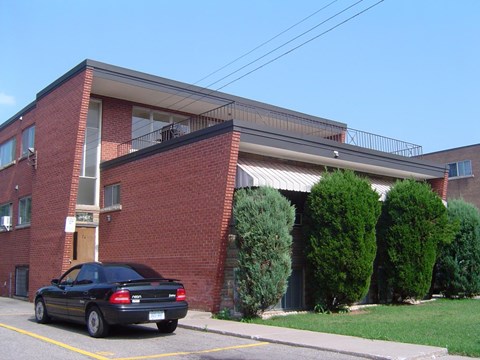 A black car is parked in a parking space in front of a red brick building.