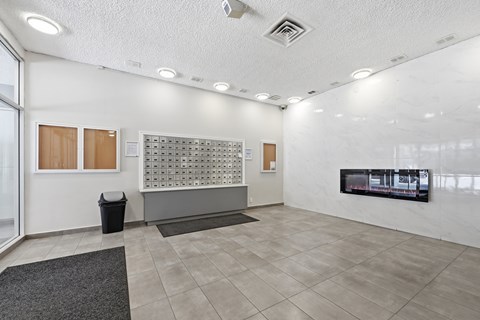 A white room with a grey carpet and a black trash can.