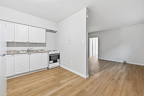 A kitchen with white cabinets and a wooden floor.