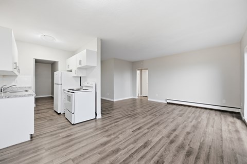 A kitchen with white appliances and wooden floors.