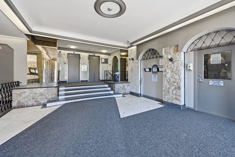 A hallway with a stone wall and metal gates.