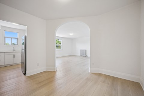 A spacious room with a window and a doorway leading to another room.