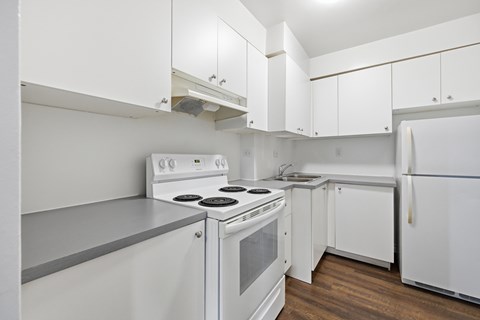 A white kitchen with a stove, sink, and refrigerator.