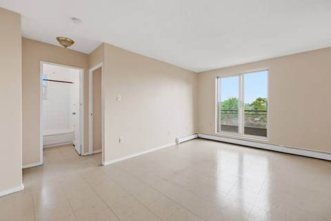 A room with a white door, a window, and a ceiling light.