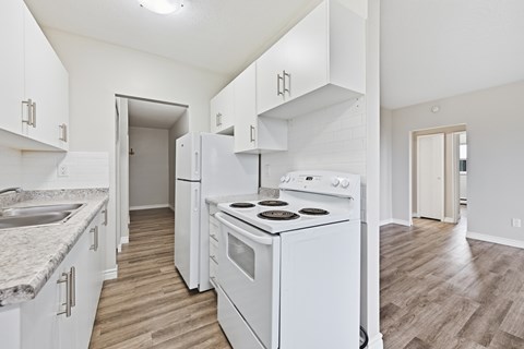 A white kitchen with a stove top oven and a sink.