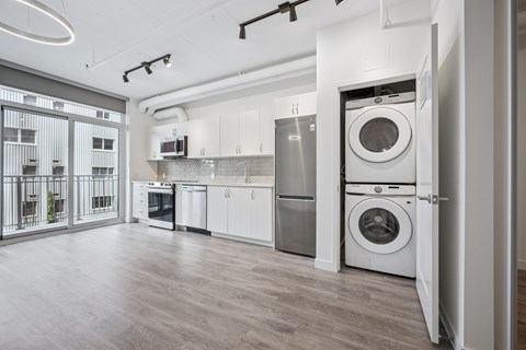 A modern kitchen with a washing machine in the doorway.