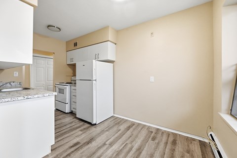 A kitchen with white appliances and wooden floors.