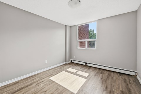 A room with a window and a wooden floor.