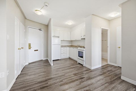 A kitchen with white cabinets and a wooden floor.
