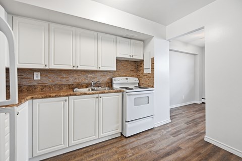 A kitchen with white cabinets and a brick backsplash.