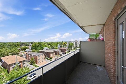 A balcony overlooks a residential area with houses and trees.