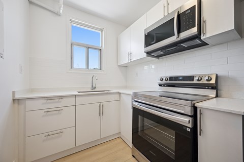 A kitchen with white cabinets and black appliances.